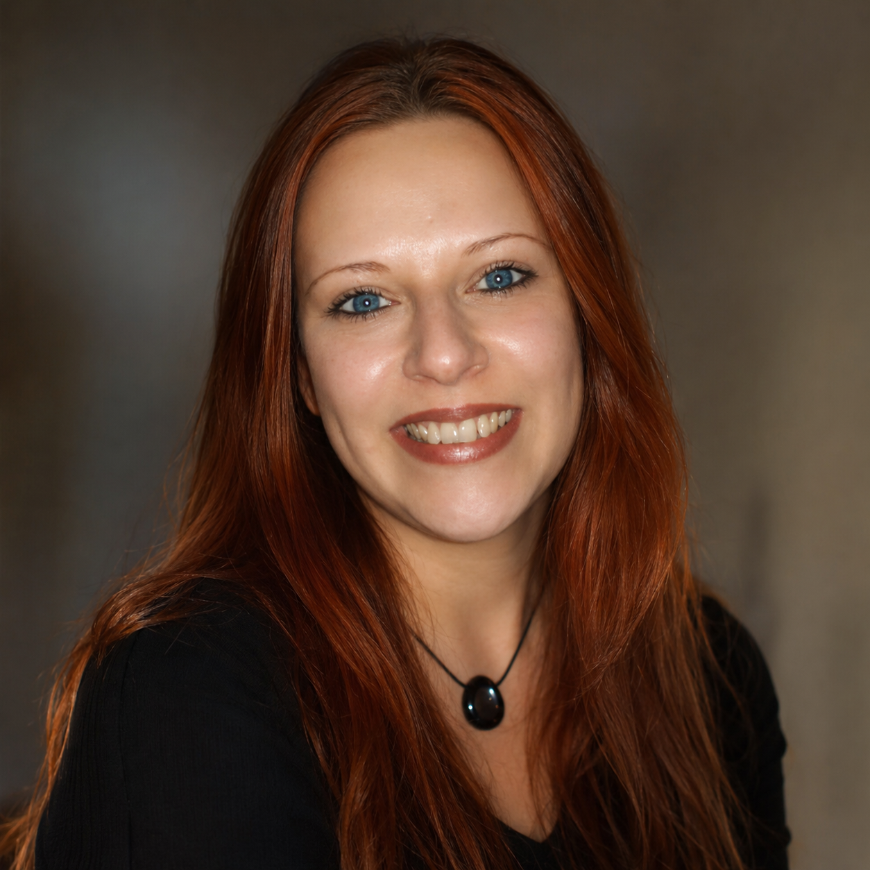 Woman with red hair and blue eyes wearing a black top and necklace against a neutral background
Susan Cibere channel medium Reiki master
